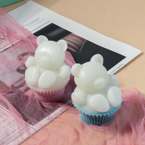 Détail de bougies parfumées ours 3D dans des caissettes roses et bleues sur une table
