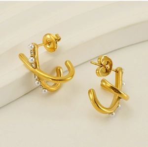 Macro shot of gold-plated cross knot C-shape earrings with pearls and crystal rhinestones