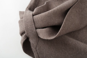 Detailed macro shot of brown knit coat with fashionable bow tie design and soft texture