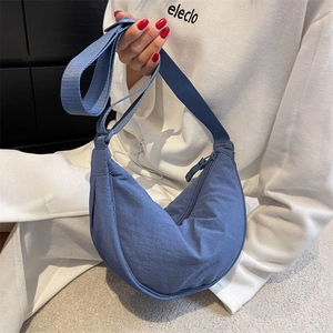 Detail view of a blue nylon crescent crossbody bag with zipper and adjustable strap
