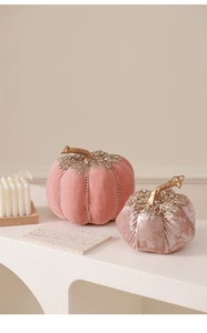 Close-up of velvet decorative pumpkins with rhinestones and golden stems in pink tones