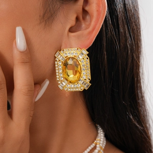 Macro shot of oversized gold baroque earrings with yellow faceted gemstone and rhinestones
