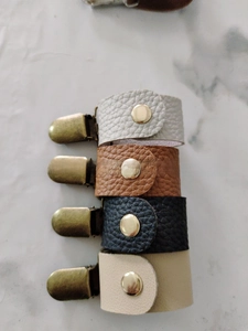 Detailansicht von vierfarbigen Hutclips aus Leder mit Goldknöpfen und Bronze-Entenschnabelclips