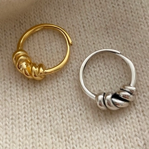 Macro shot of S925 sterling silver knotted rings in gold and silver on knit fabric