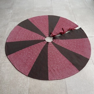 Detail of red and black knitted Christmas tree skirt with festive radial stripe pattern