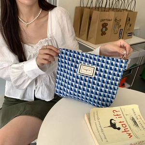 Gros plan d'une trousse en tweed bleu et blanc avec étiquette Pleasant Time sur table