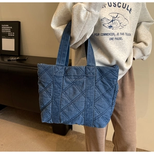 Vue détaillée du sac cabas en denim bleu avec surpiqûres en losanges classiques
