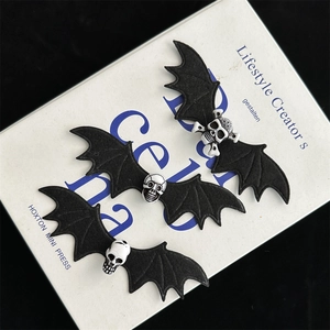Set of three gothic bat wing hair clips with skull center on a white book surface