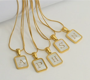 Close-up of golden snake chains with white shell square letter pendants A P H S N