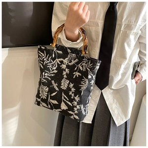Detail of bamboo handles on a black and white floral linen jacquard handbag