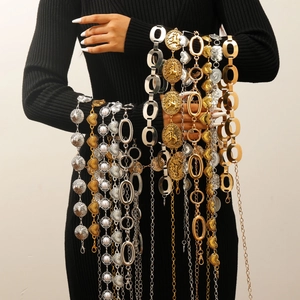 Vintage metal waist chains with heart charms and pearls on a black dress backdrop