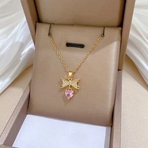 Close-up of a gold bow-knot necklace with sparkling diamonds and a pink heart pendant