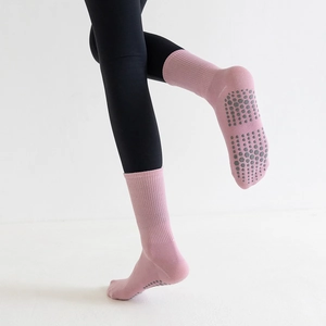Detail of pink crew yoga socks featuring gray non-slip silicone grips on the soles