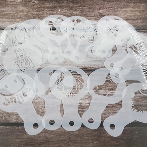 Detailed view of 20-piece plastic coffee stencils with festive Christmas patterns on wood