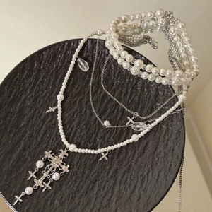 Elegant multi-layer pearl necklace with silver cross pendant on a black tray