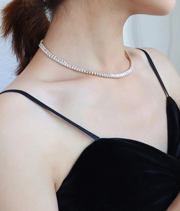 Close-up of baguette-cut zircon tennis necklace in gold plating worn by a model