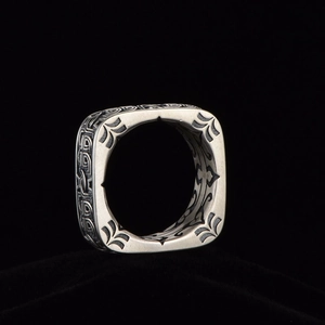 Vintage oxidized silver ring with square face and intricate totemic carvings on black velvet