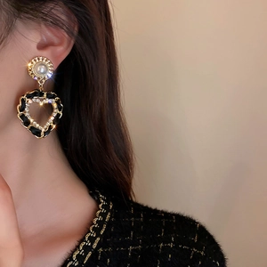Gros plan de boucles d'oreilles cœur en cuir tressé et cristaux portées par un mannequin