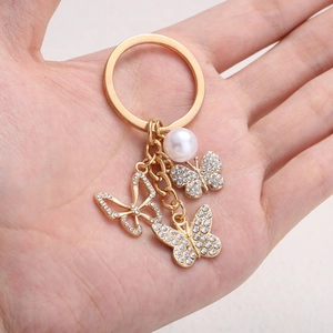 Detailed close-up of golden butterfly keychain with inlaid rhinestones and pearl
