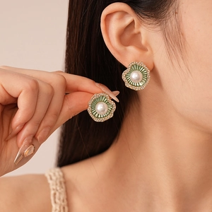 Gros plan d'une boucle d'oreille fleur en émail vert avec perles et diamants