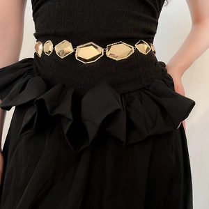Détail d'une chaîne de taille dorée en métal à facettes géométriques sur un mannequin