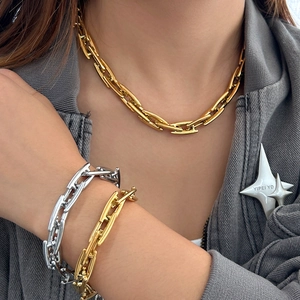 Close-up of trendy layered gold and silver titanium steel link necklaces worn by a model