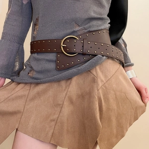 Detail of vintage brown leather waist belt with gold studs and round buckle on a model