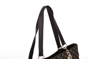 Close-up of textured leather handle with gold metal rings on a patterned tote bag