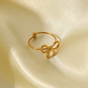 Close-up of golden butterfly open ring on elegant champagne silk fabric background