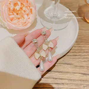 Detail view of pearl drop earrings featuring cream bows and sparkling rhinestones