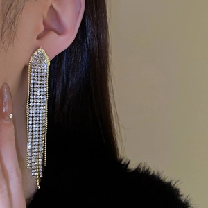 Detail of long geometric tassel earrings with rows of crystals on a gold base