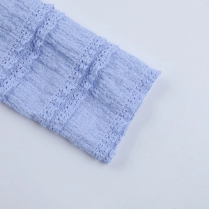 Detail of light blue dress fabric featuring natural crinkle texture and hollow lace trim