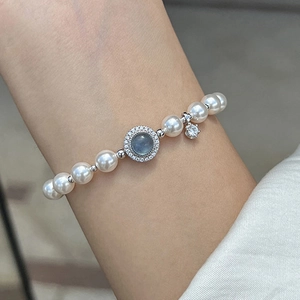 Silver pearl bracelet with blue zircon centerpiece and star pendant on woman wrist
