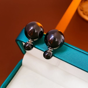 Macro shot of elegant black double pearl stud earrings with silver metal on jewelry box