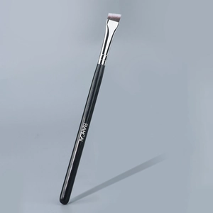 Gros plan d'un pinceau à sourcils biseauté ultra-fin avec manche en bois noir brillant