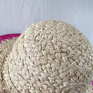 Détail du chapeau en raphia tressé main avec texture naturelle et bande fuchsia contrastée