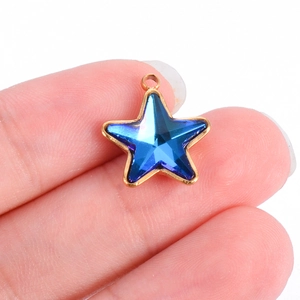 Gold-plated stainless steel star pendant with blue glass insert held for scale