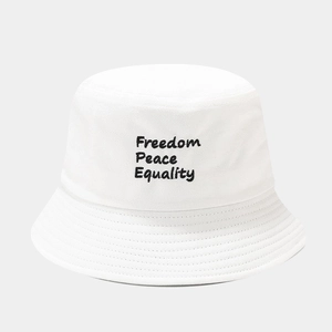 Gros plan sur un bob en toile blanche avec broderies noires Freedom, Peace et Equality