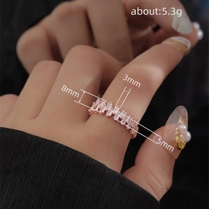 Roségoldener geometrischer Ring mit Zirkonia-Steinen im Rechteckschliff am Finger