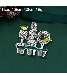 Detail view of bird and plant brooch with green enamel and size measurements