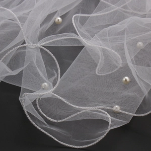 Close-up detail of white bridal wedding veil featuring delicate mesh fabric and hand-sewn pearls