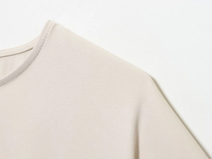 Detailed close-up of apricot textured blouse showing puffy sleeve seams and neckline