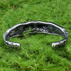 Vintage stainless steel open skull bracelet with intricate textured engravings on moss