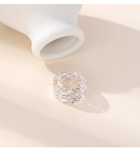 Macro detail of silver irregular wire wrapped nest ring on minimalist ceramic plate