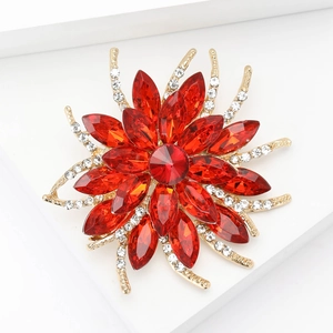 Close-up of golden flower brooch with red crystals and pavé white diamonds detail