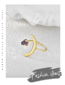 Top view of gold moon ring featuring raw purple amethyst stone on white textured surface
