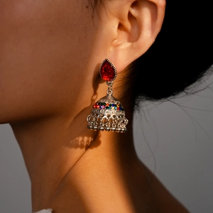 Detailed macro view of vintage Jhumka earrings with red drop stone and colorful accents