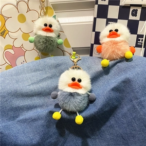 Detailed view of colorful plush duck keychains in green, pink, and blue on denim cloth