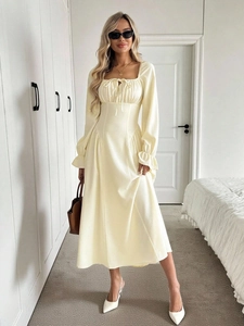 Detail of square neck and tie-up design on a soft beige long sleeve midi dress