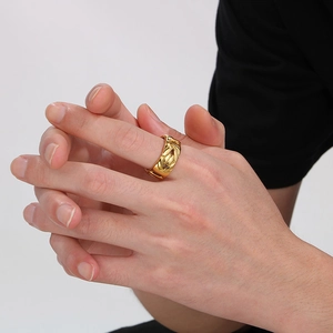 Close-up of a wide gold woven stainless steel V-shape ring on a model's hand